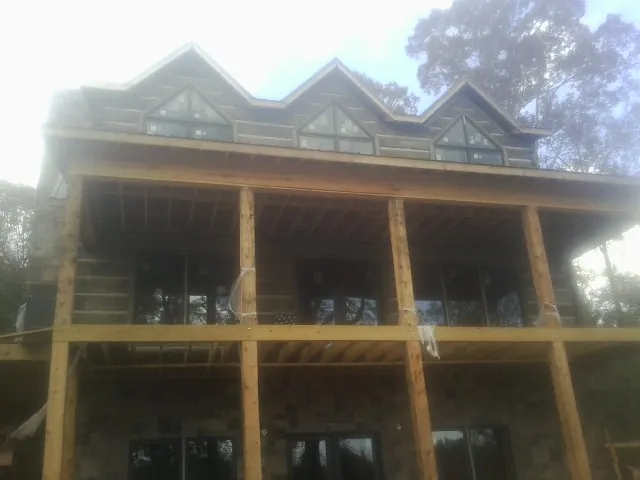 Dormers and porch framing on a large log home under construction — Roof Coating work by our crew in Bloomville