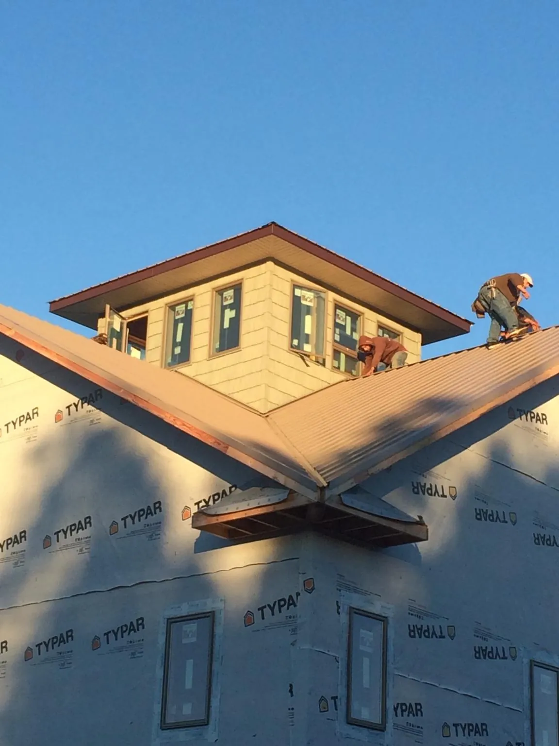 Roofers working around a rooftop cupola on a new metal roof at sunset — Roof Waterproofing in Bloomville by Roofing Brothers